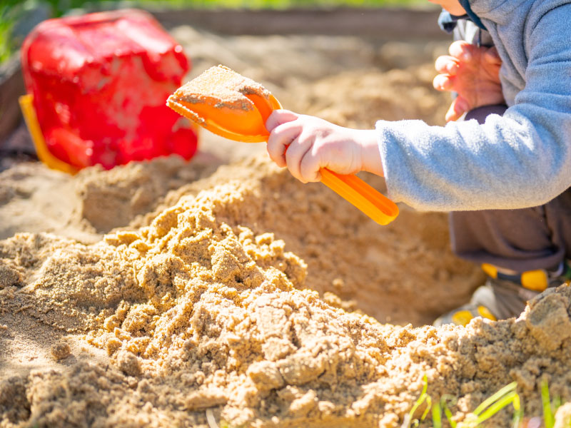 Das Bild zeigt ein Kind auf einem Spielplatz, in einer Sandkiste und ist auf der Seite der Zielgruppe der Spiba Nord GmbH zu finden